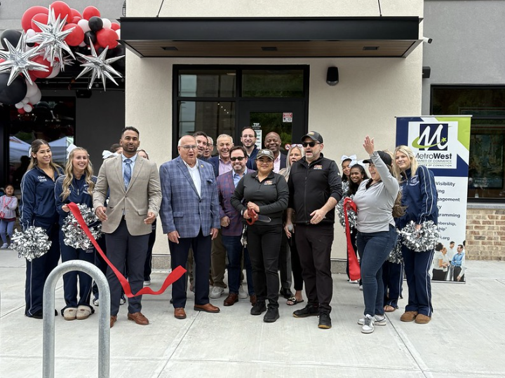 A Cane's employee cuts the ribbon in front of the restaurant alongside Chamber of Commerce members, Mayor of Framingham Charlie Sistsky, Framingham High School cheerleaders and other Cane's employees.
